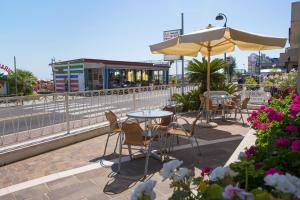 un patio con mesas, sillas y una sombrilla en Hotel Gorini, en Bellaria-Igea Marina