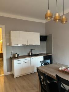 a kitchen with white cabinets and a table with chairs at Apartament Ignacy in Brodnica