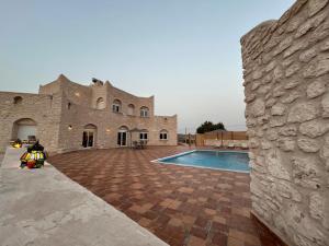 a stone building with a swimming pool in front of it at Dar Éthiqua in Essaouira