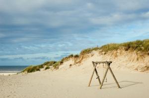 a beach with a swing in the sand at Strandhotel Terschelling in Formerum