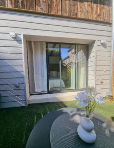 Suite cosy indépendante Evasion env Colmar في فينتزنهايم: مزهرية بها زهرة على طاولة في الفناء