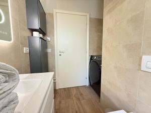 łazienka z pralką i suszarką obok drzwi w obiekcie Appartamento in città con Giardino e Piscina privati w Bergamo