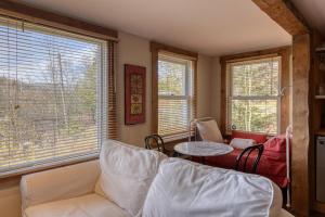 ein Wohnzimmer mit einer Couch und einem Tisch und Fenstern in der Unterkunft Cozy 3 bedroom cottage 8 min from North side Tremblant in Lac-Superieur