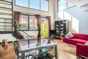 un soggiorno con tavolo in vetro e divano rosso di RED LOFTY Milano- Loft moderno comodo per Ippodromo, San Siro, Rho Fiera-MiCo e Politecnico, parking a Milano