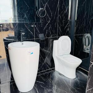a bathroom with a white toilet and a black wall at Cité La Vie in Douala