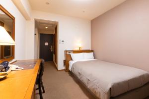 a hotel room with a bed and a desk and a desk at Hotel Bel Air Sendai in Sendai