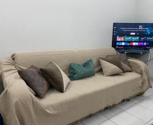 sofá con almohadas y sala de estar con TV. en Lilly Apartament, en Pogradec