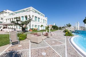un edificio bianco con sedie e piscina di Grand Hotel Da Vinci a Cesenatico