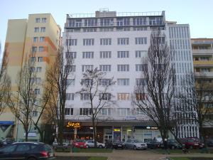 un gran edificio blanco con coches aparcados en un aparcamiento en HELLO Gdynia Hostel, en Gdynia