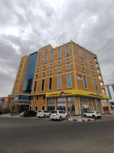 een groot gebouw met auto's ervoor geparkeerd bij Mirada Purple Najran Hotel in Najran