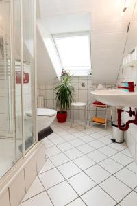 Baño blanco con bañera y lavamanos en Gästehaus Hauser en Rust