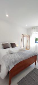 a bedroom with a large bed with white walls at Casa Maria Olímpia in Nazaré