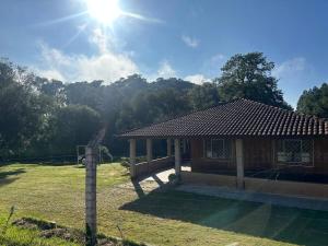 a house in a field with the sun in the sky at Recanto Amado in Araucária