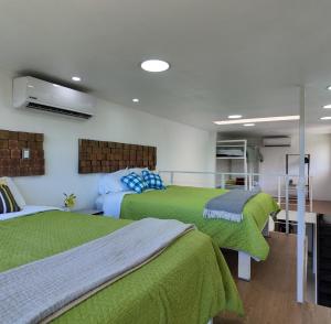 two beds in a room with green blankets at Las Terrazas Suites Studio Apartment in San Salvador