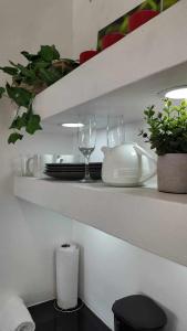 een witte plank met glazen, borden en planten bij Las Terrazas Suites Studio Apartment in San Salvador +7 foto's