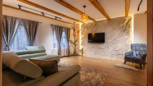 a living room with a couch and a tv on a stone wall at Sun x Mountains - Old Town in Braşov