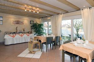 a dining room with tables and chairs and windows at Gästehaus Hauser in Rust