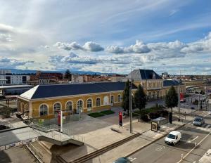 a large yellow building with a parking lot in a city at Face à la gare - Chambre 3 in Roanne +3 photos