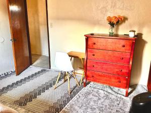 a red dresser with a vase of flowers on top of it at Karibu House in Tucson