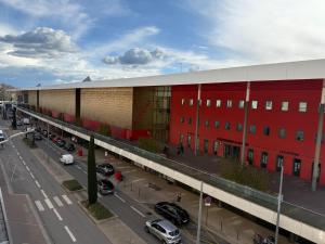 a large red building with cars parked in a parking lot at Face à la gare - Chambre 3 in Roanne
