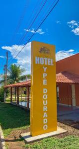 a yellow hotel sign in front of a building at Ipê Dourado Hotel in Natividade