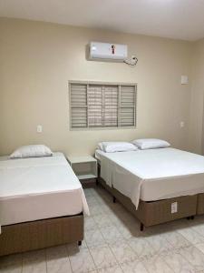 two beds sitting next to each other in a bedroom at Ipê Dourado Hotel in Natividade