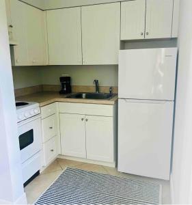 a kitchen with white cabinets and a sink and a refrigerator at Fernando Flats in Palm Beach Shores +37 photos