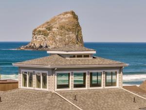 a house on the beach with a rock in the background at Pacific Watch in Pacific City