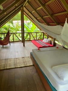 a bedroom with two beds and a hammock on a porch at La Aldea del Primitivo in Nuquí