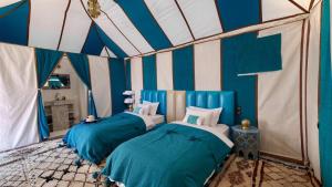 two beds in a room with blue and white stripes at Nada luxury desert camp in Merzouga