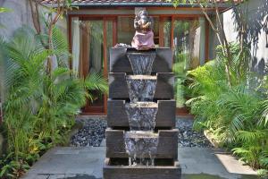 a fountain in the middle of a garden at Umah D Meranggi in Banjarangkan +8 photos