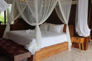a bedroom with a bed with white drapes at Umah D Meranggi in Banjarangkan
