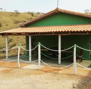 a green building with a chain fence in front of it at Cachoeira do Galvão in Delfinópolis