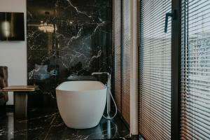 Łazienka z białą wanną i czarną ścianą w obiekcie Highgarden Hotel w mieście Tbilisi City