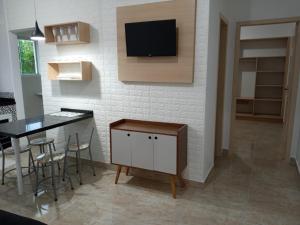 a kitchen with a table and a tv on a wall at Apartamento na Praia de Pontal do Sul- Pontal do Paraná in Pontal do Paraná
