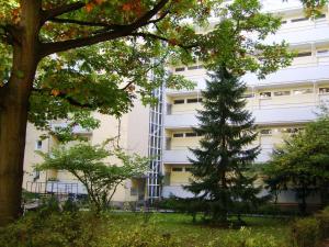 un edificio blanco alto con un árbol delante de él en Nikol Apartments, en Berlín