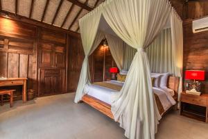 a bedroom with a canopy bed and a desk at TUJUH Angel by GenuineHost in Ubud +37 photos