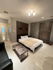 Saijō-chōにあるHotel JOYCEのベッドルーム(大型ベッド1台、コーヒーテーブル付)