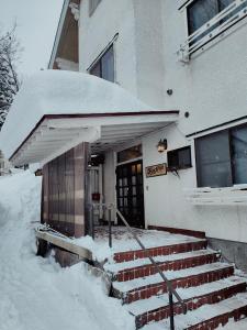 a snow covered building with stairs in front of it at Hotel Foxtrot Hakuba in Hakuba