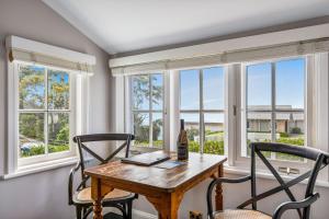 ein Esszimmer mit Tisch und Stühlen und Fenstern in der Unterkunft Cottage 1 Hyams Beach Seaside Cottages in Hyams Beach