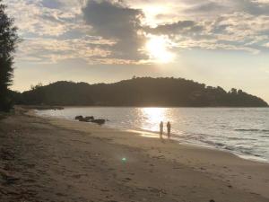 two people standing on a beach near the water at Cabana Chalet Cherating in Cherating +8 photos