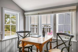a dining room with a table and chairs and windows at Cottage 2 Hyams Beach Seaside Cottages in Hyams Beach +15 photos