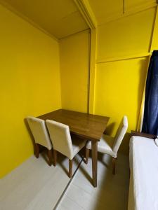comedor con paredes amarillas y mesa y sillas de madera en ホテルペナ101, en Tokio