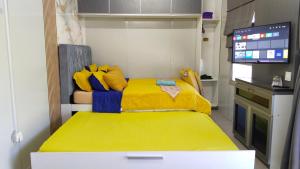 a small room with a yellow bed and a tv at Casa LiLa Tiny Cabin Studio Stay & Pool Kota Bharu,free wifi,free parking in Kampong Seribang