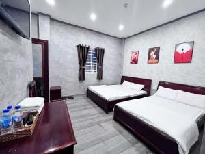 a hotel room with two beds and a desk at Trung Hau Hotel in Can Tho