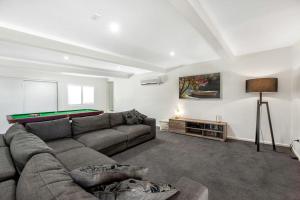 a living room with a couch and a pool table at Malibu Palms - Echuca Holiday Homes in Moama +15 photos