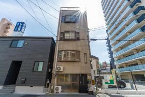 ein hohes Gebäude in einer Stadtstraße mit Gebäuden in der Unterkunft Cozy condo for 2 PPL near Teradacho Sta 4 min walk cecilia301 in Osaka