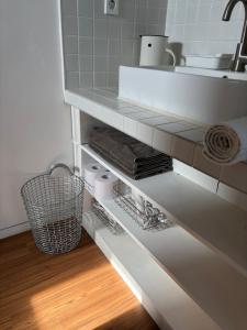 a bathroom with a sink and a shelf with towels at Kimnung House Anmok in Jeju +16 photos