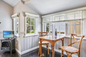 a dining room with a table and chairs and a television at Cottage 5 Hyams Beach Seaside Cottages in Hyams Beach +15 photos