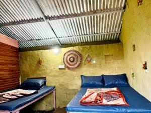 a small room with two beds and a wall at Thatharana Trek by Mountain Hikers - Mudhouse & Cafe in Dharmsāla